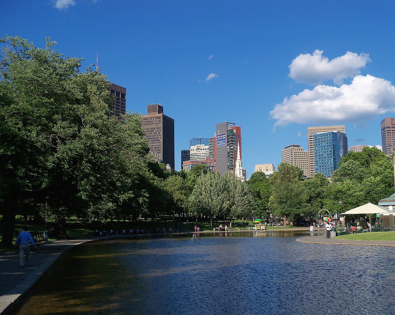 The Frog Pond on Boston Common in summer, with the downtown towers beyond the trees