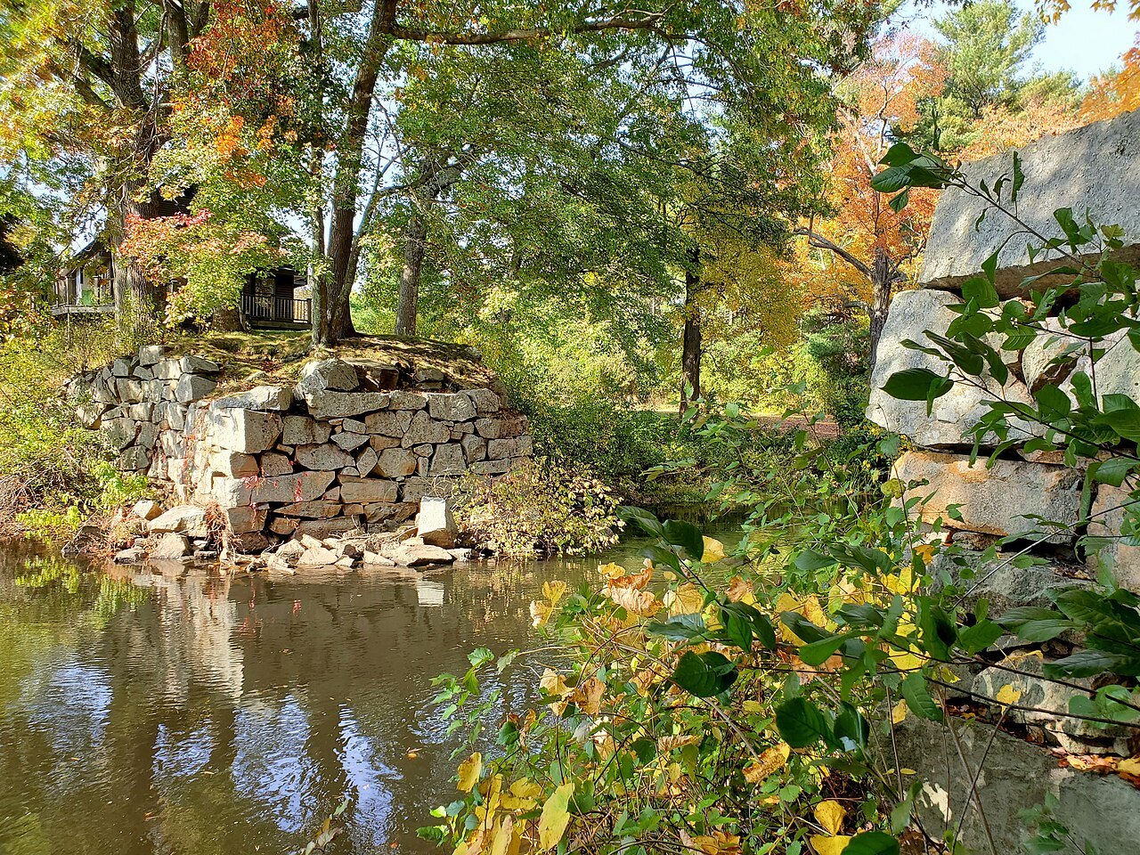Autumn trees over old stone abutments by the Charles River in Medway