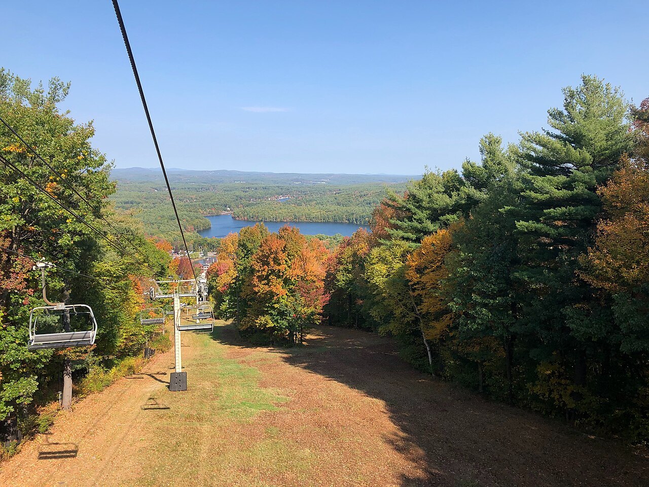 A chairlift climbing through early autumn color at Wachusett Mountain