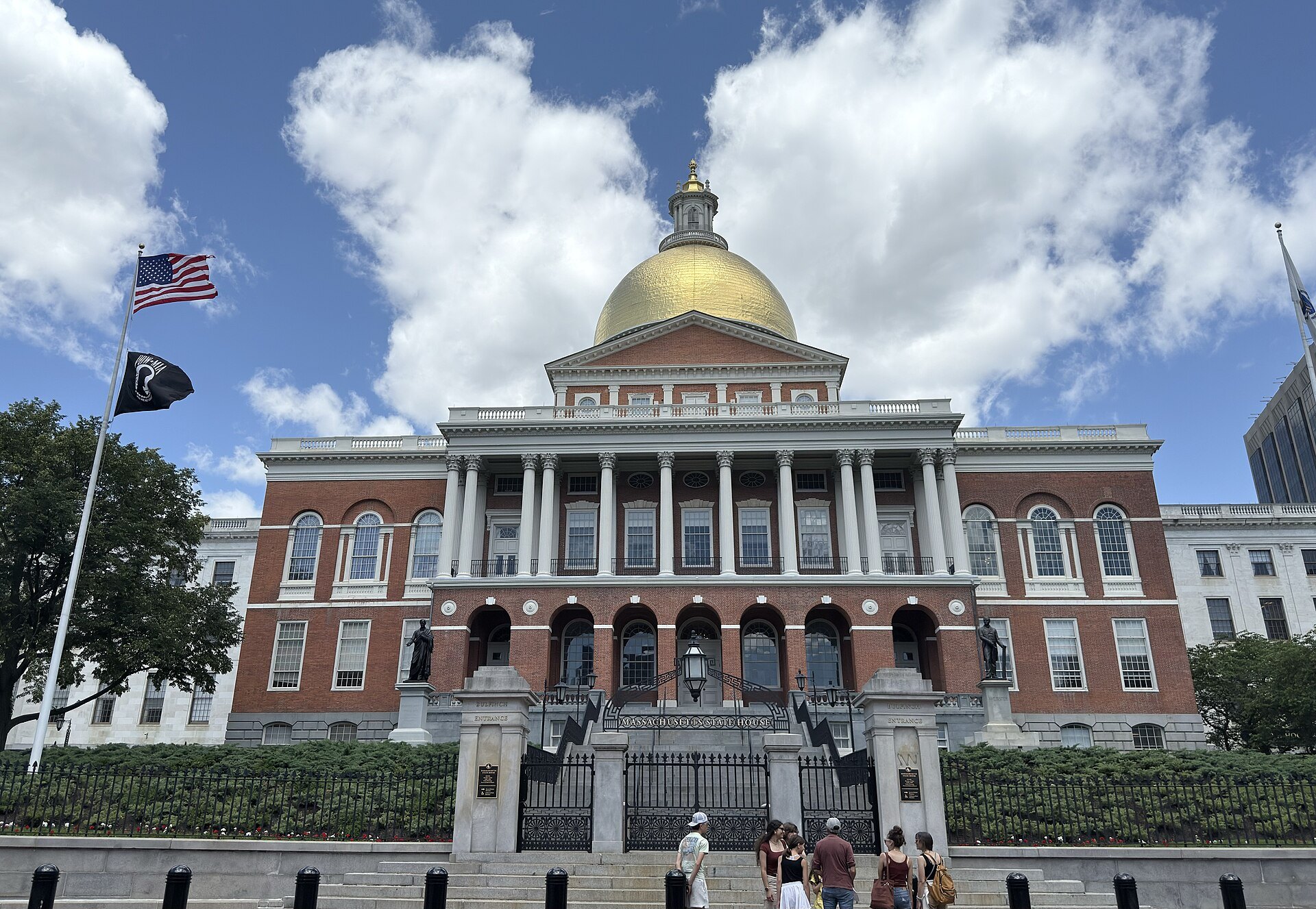 The State House under a summer sky, its gold dome above the red brick and white columns