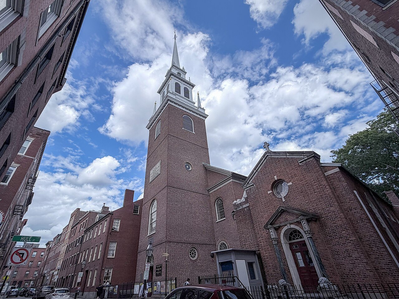 The brick tower and white steeple of the Old North Church above a North End street