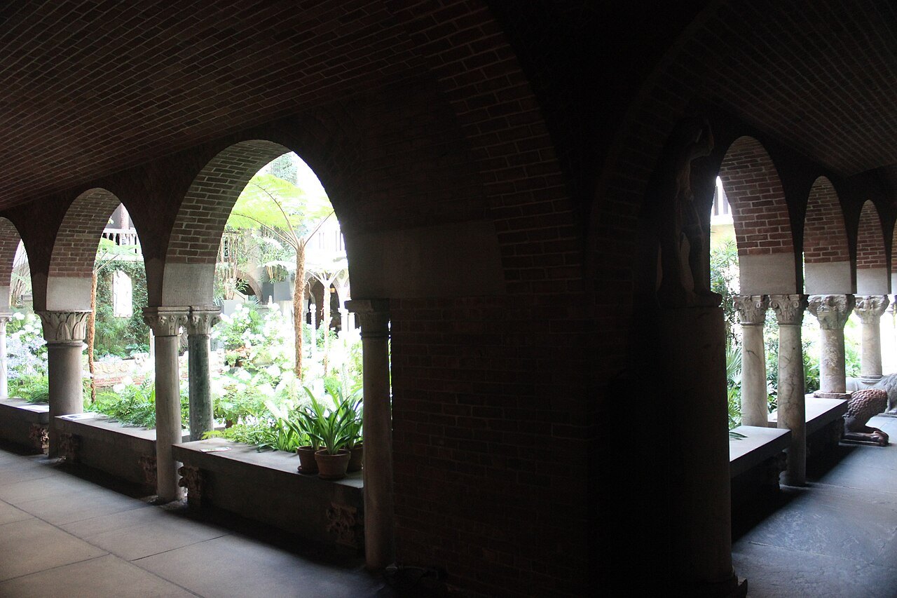 Arches of a cloister walk opening onto the sunlit courtyard