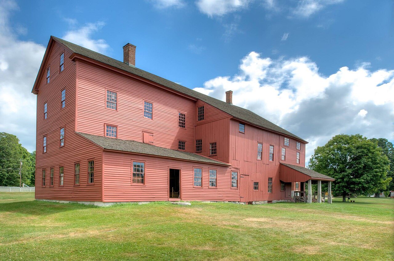 The red clapboard Laundry and Machine Shop in the summer grass