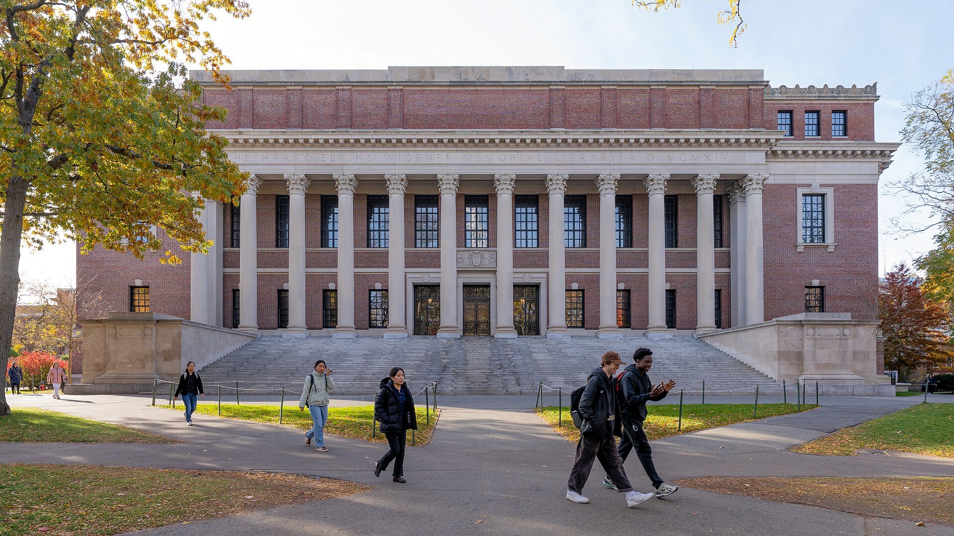 The columned front of Widener Library across the Yard, students crossing in autumn