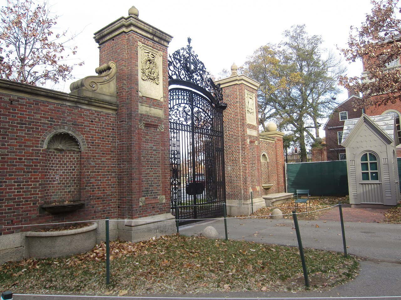 One of the Yard's gates of brick and wrought iron, fallen leaves at its foot