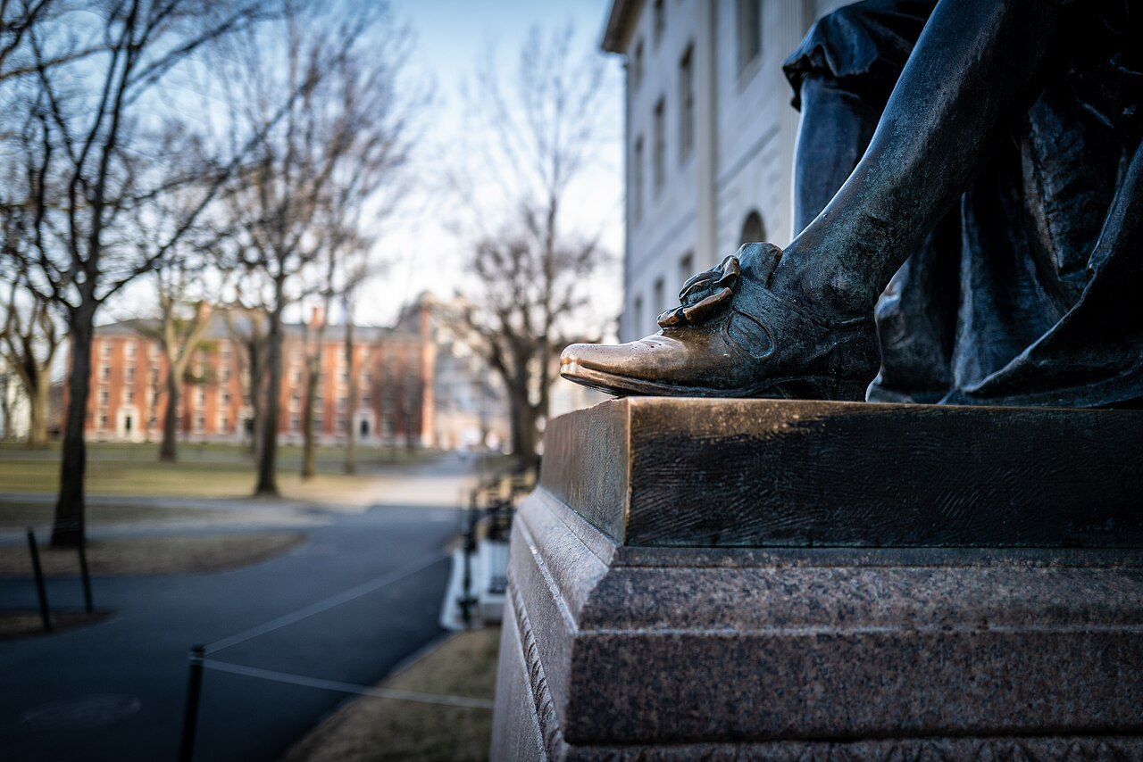 The bronze toe of the John Harvard statue, rubbed bright by visitors, at the edge of the Yard