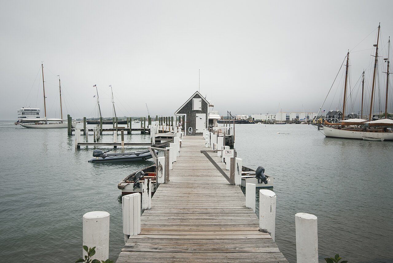A wooden pier in Vineyard Haven harbor on a foggy morning, sailboats at their moorings