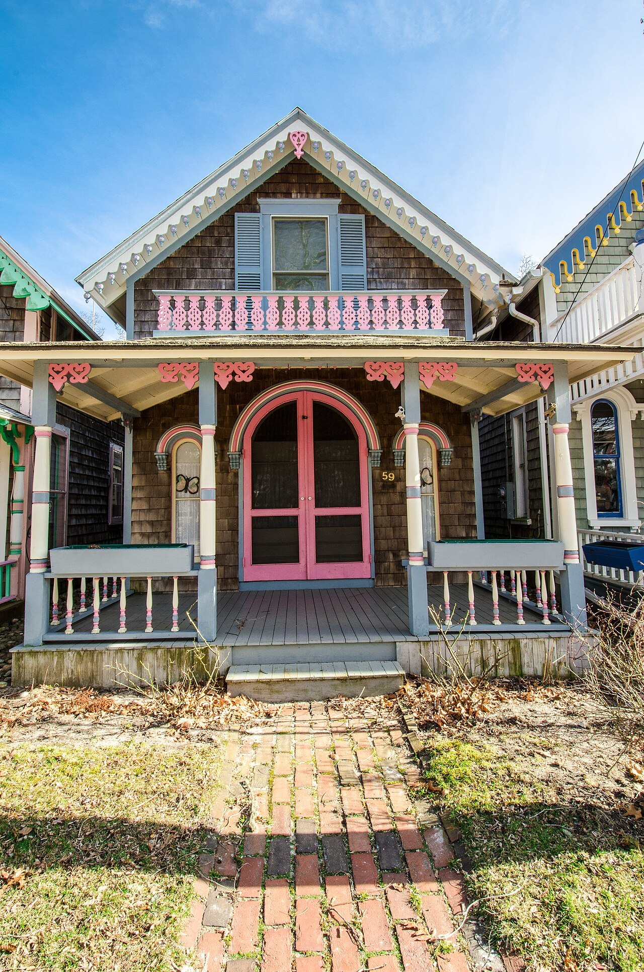 A gingerbread cottage with a pink door and a brick path in Oak Bluffs