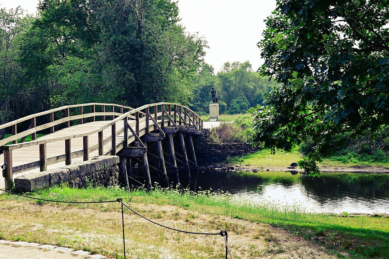 The arched North Bridge seen from the grassy riverbank on a summer day