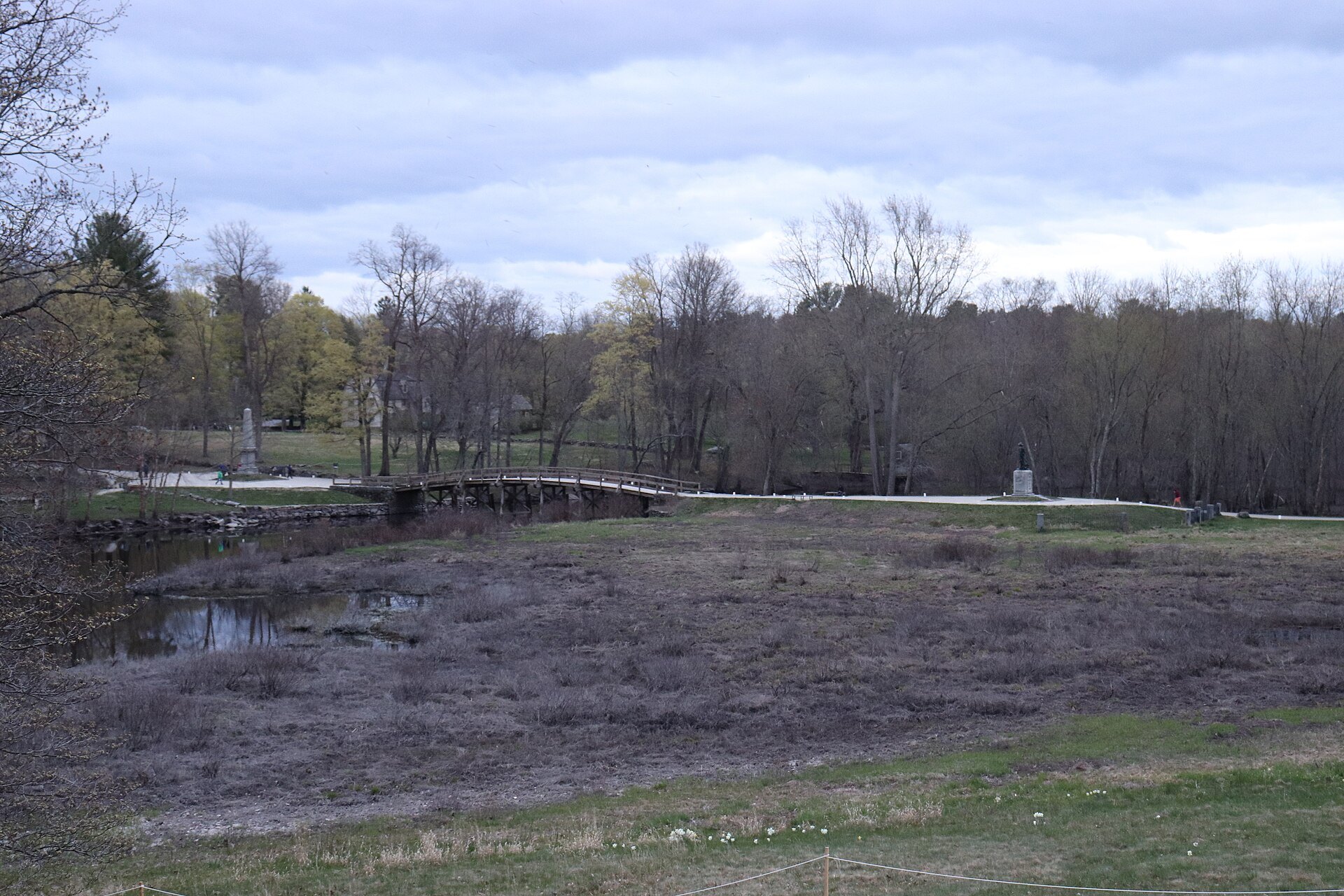 The North Bridge and its meadow from the overlook by the Buttrick gardens, trees still bare in spring