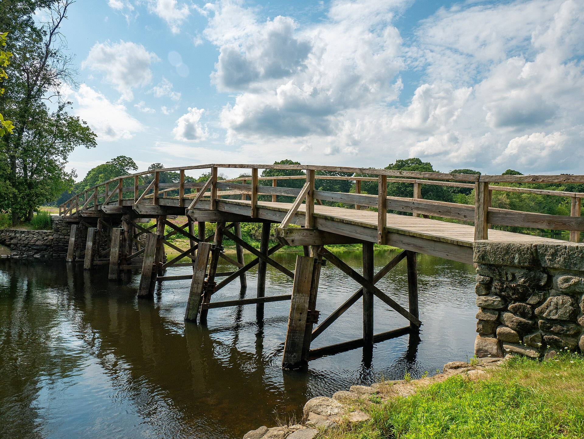 The wooden North Bridge over the Concord River under a sky of summer clouds