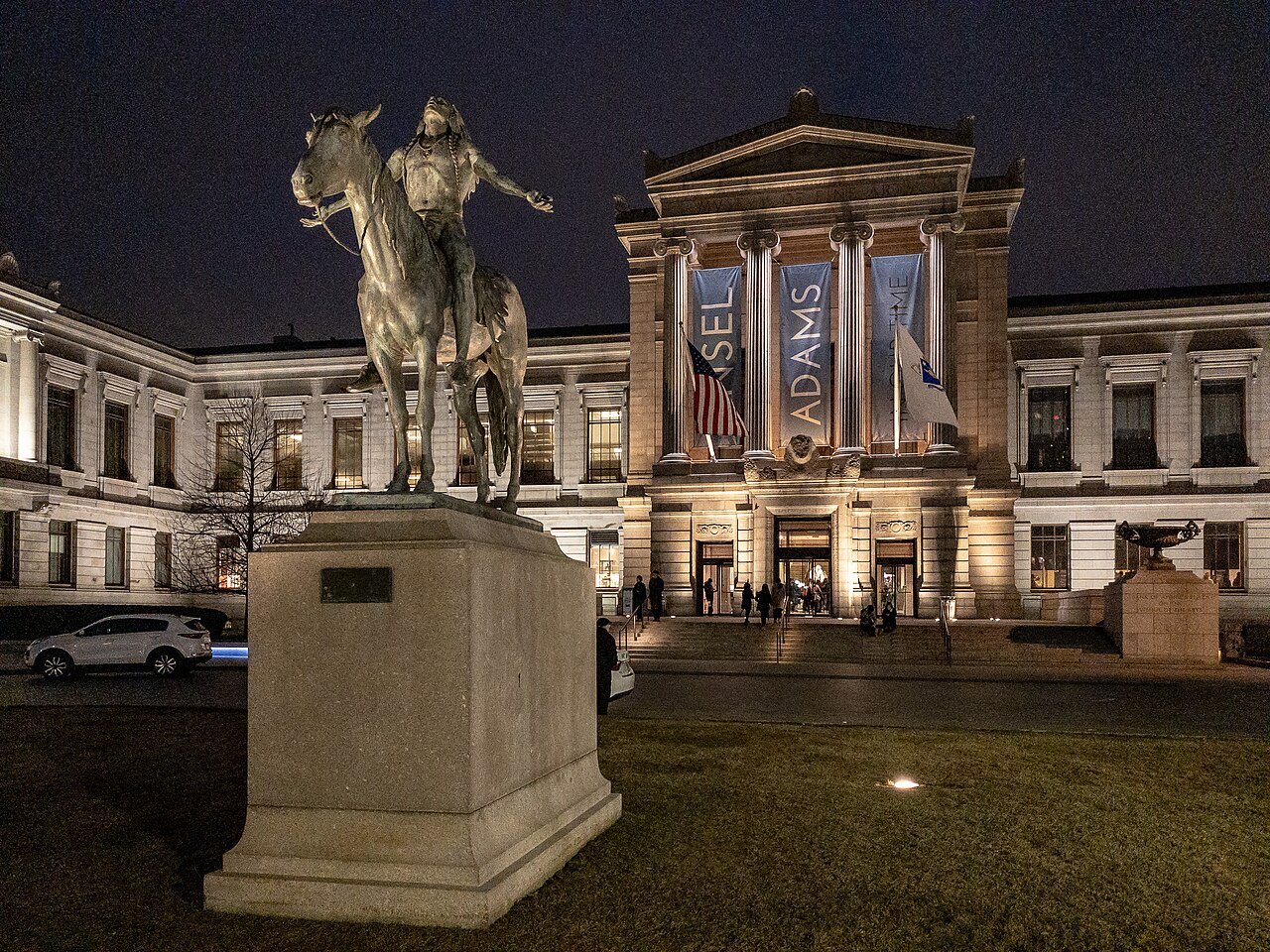 The museum's Huntington Avenue entrance lit at night behind the mounted bronze