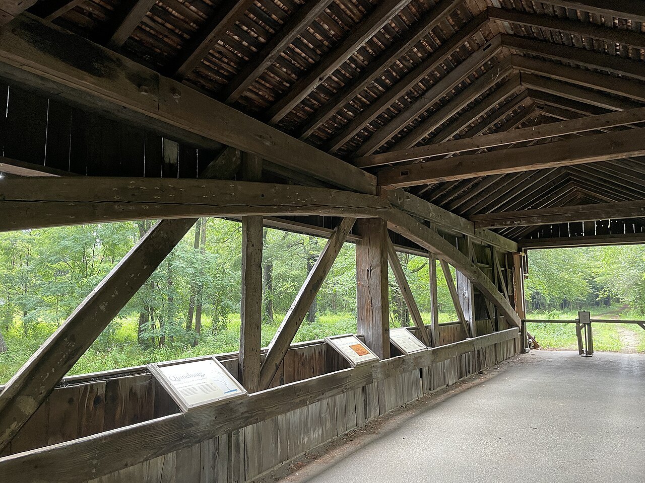 Inside the covered bridge over the Quinebaug River, its timber trusses framing the meadow