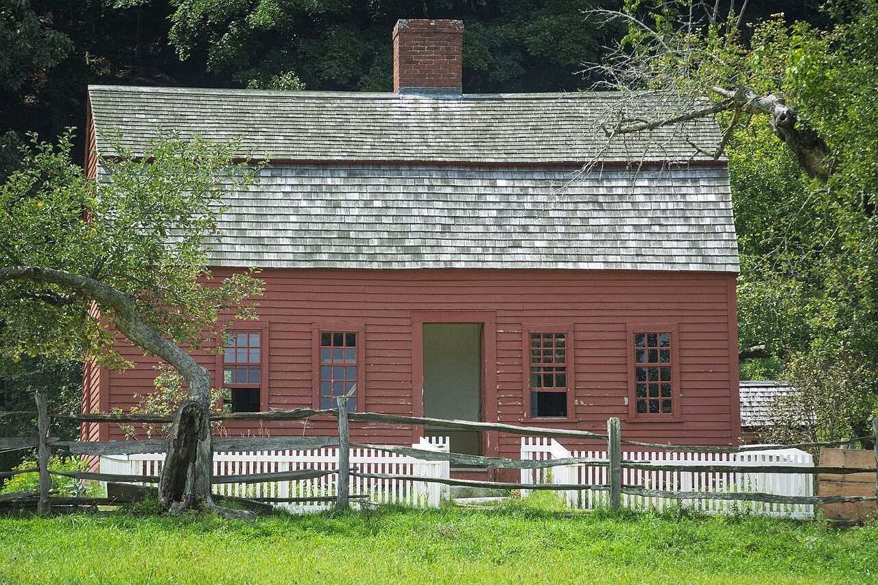 The red farmhouse of Freeman Farm behind its white picket fence