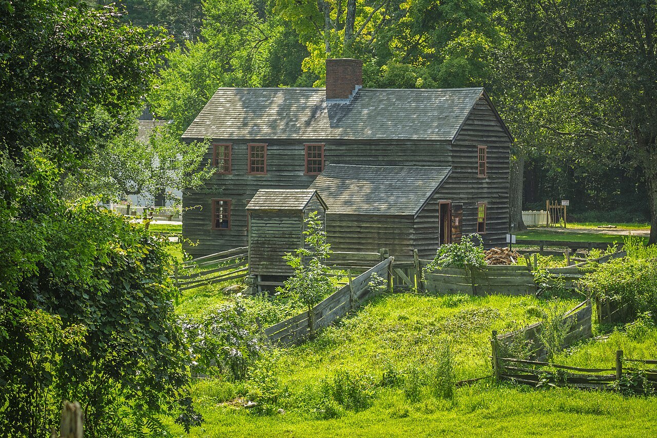 The weathered Fenno House among green trees at Old Sturbridge Village