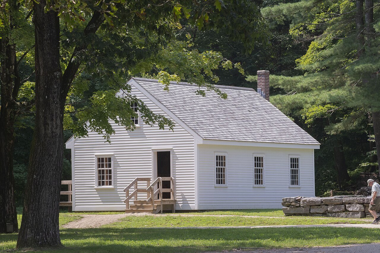 The white Cabinetmaking Shop in the shade of tall trees