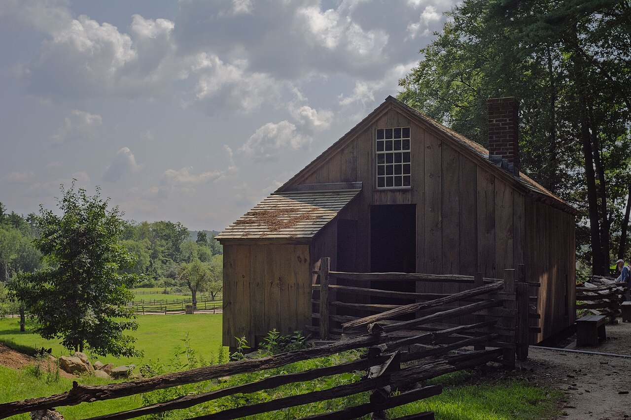 The weathered board Allen Piggery beside a rail fence