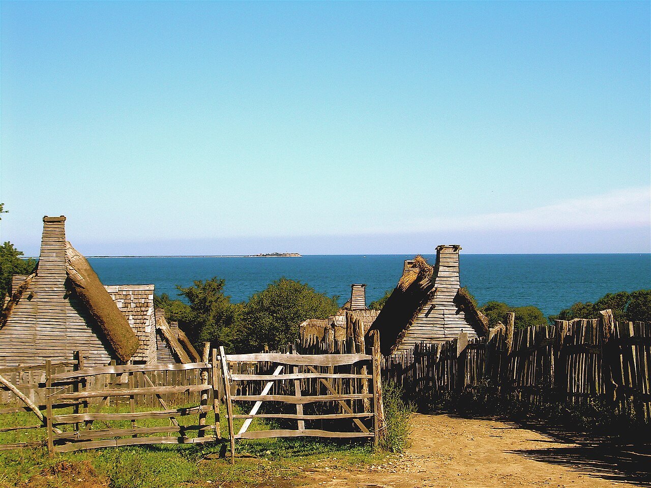 Thatched roofs and a wooden gate in the village, the sea beyond