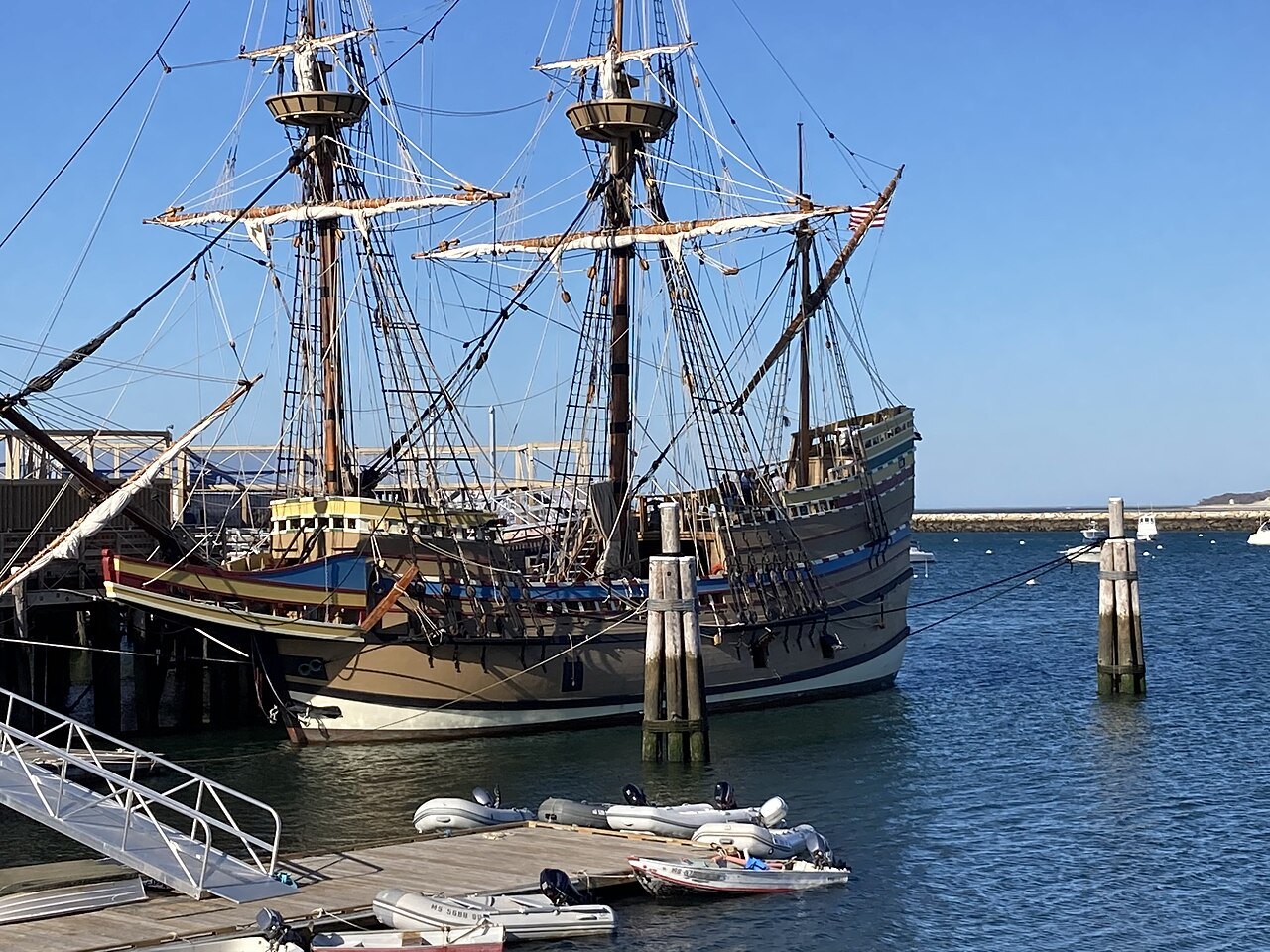 The Mayflower II alongside her pier, her rigging against a clear sky