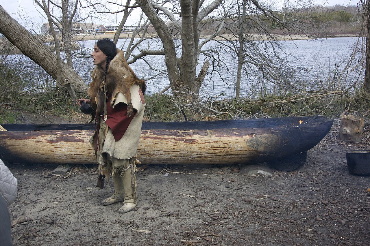 A Wampanoag interpreter beside a dugout canoe at the Homesite