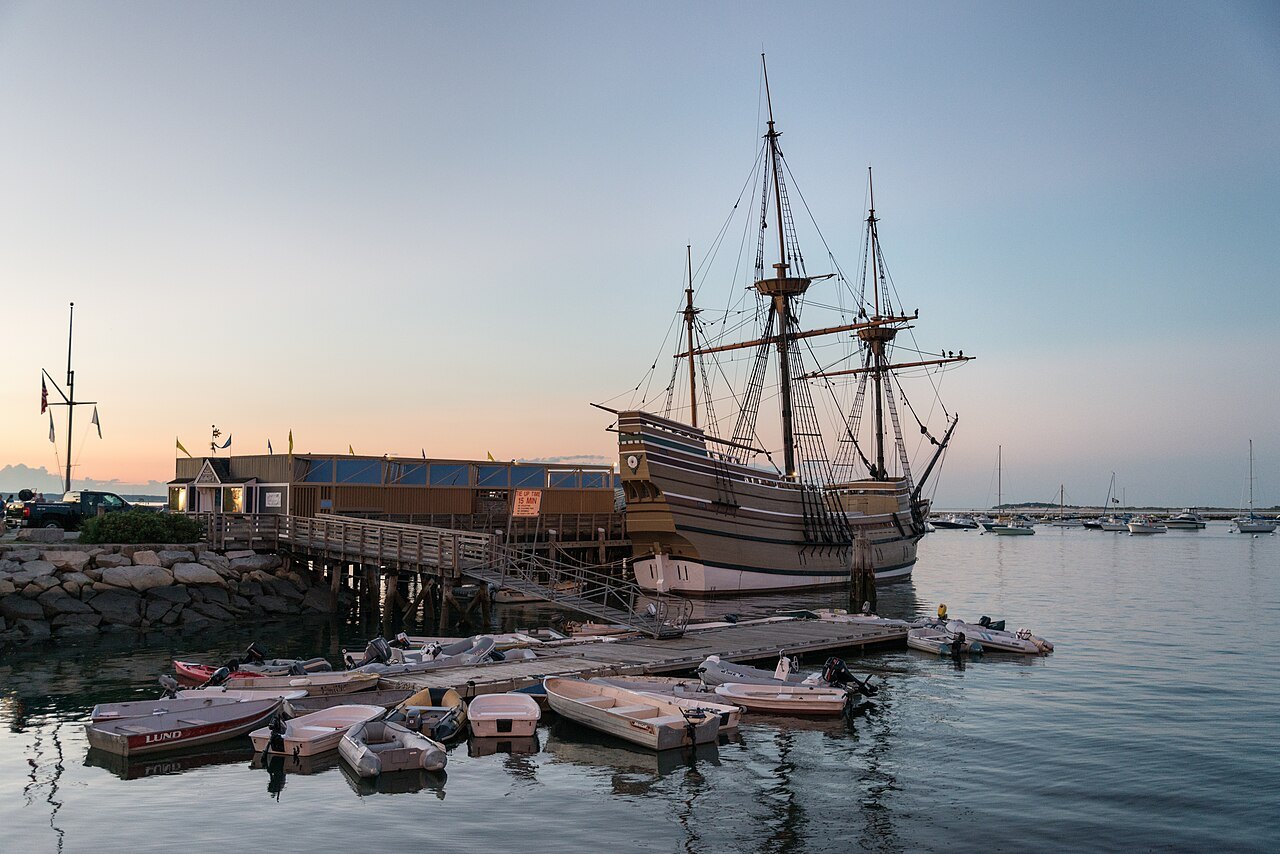 The Mayflower II at dusk, small boats drawn up by the pier