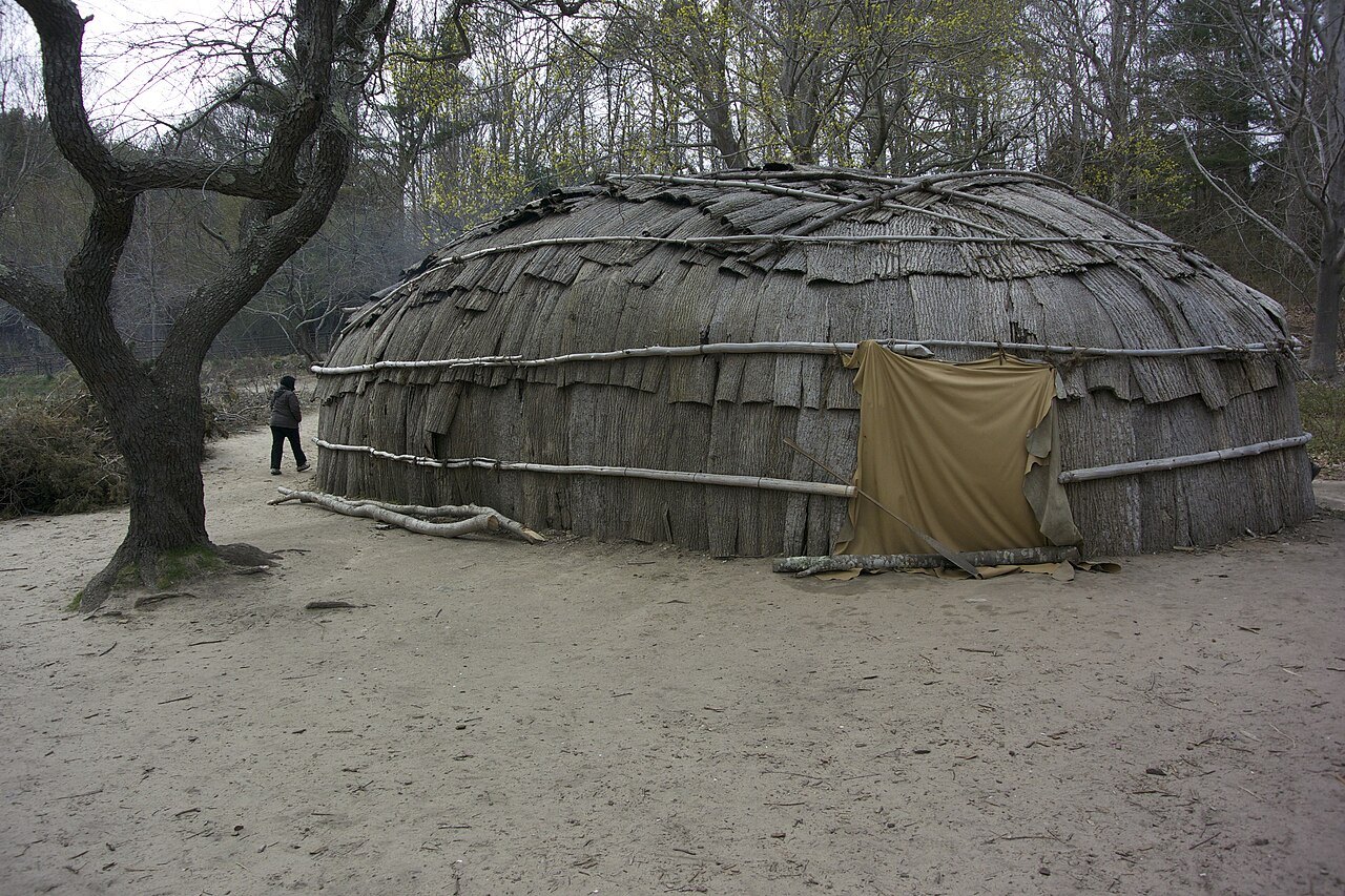 A bark-covered house at the Wampanoag Homesite among the trees