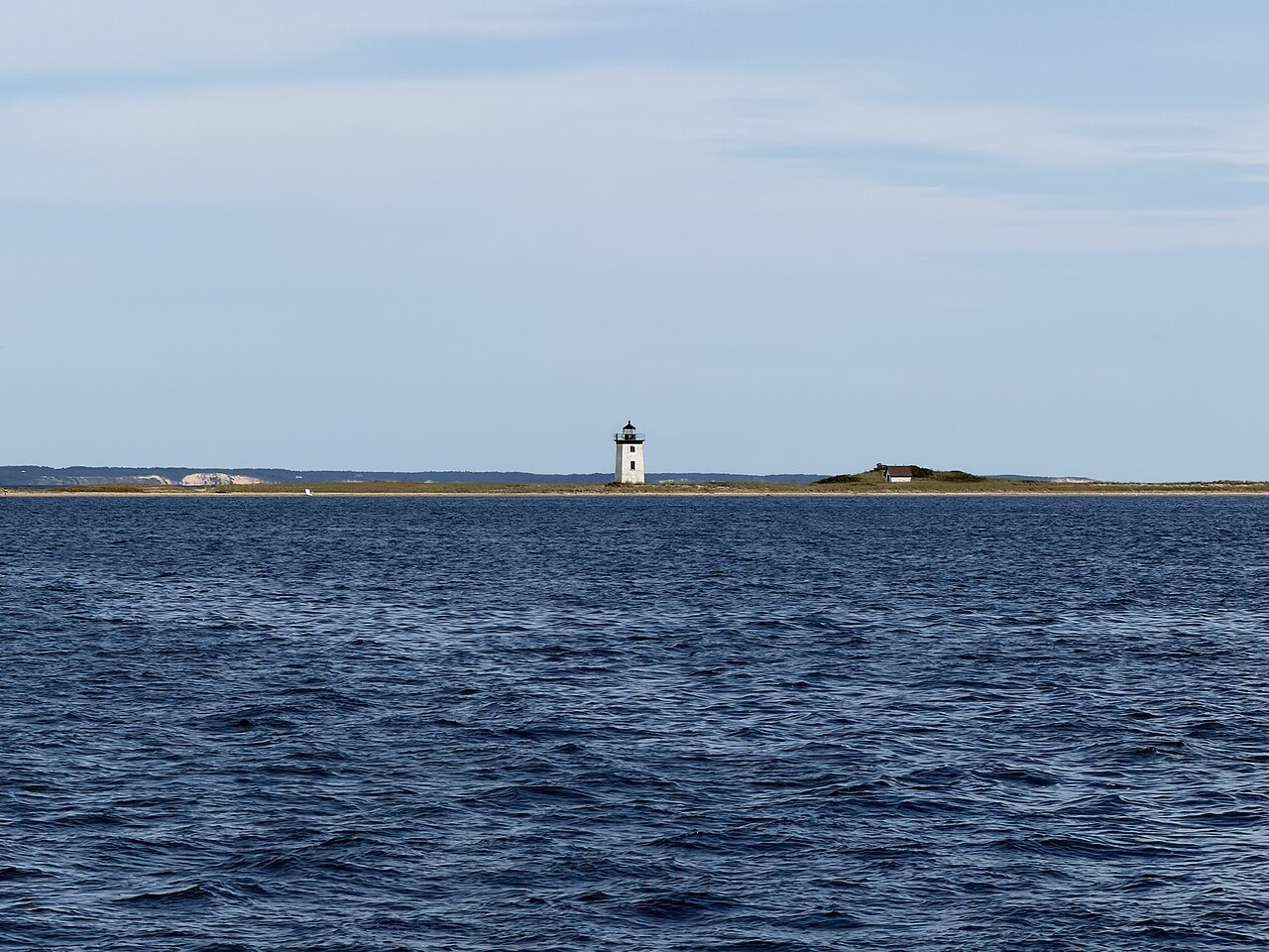 Long Point Light, a small white tower at the tip of the sand spit across the harbor
