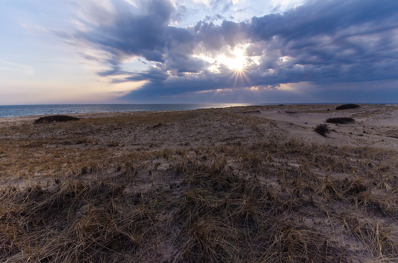 Sunset through storm clouds over the grass of Race Point