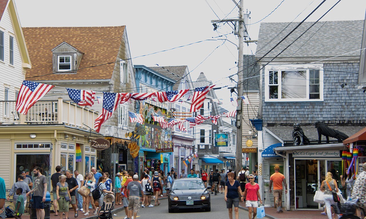 Flags and summer crowds on Commercial Street between shingled shops