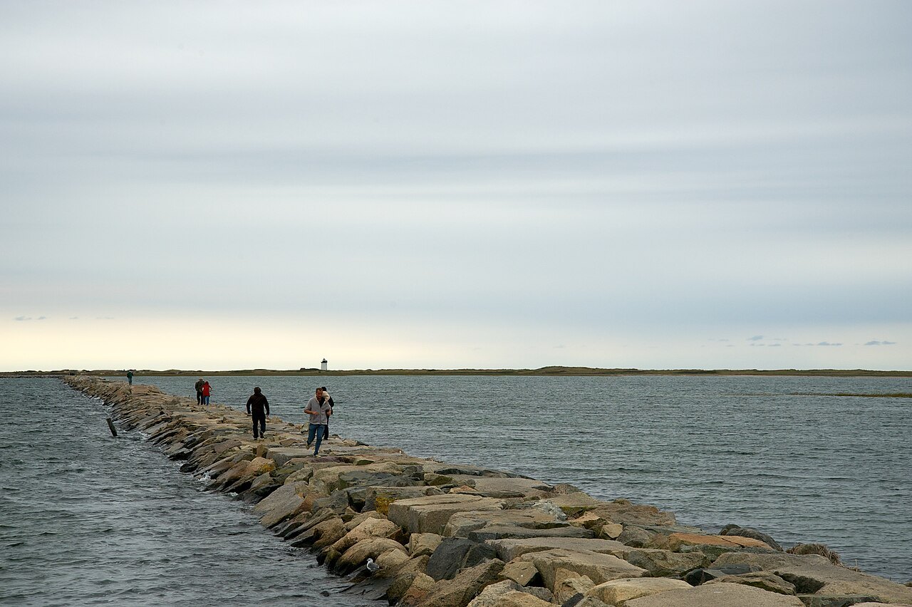 Walkers on the stone breakwater at the west end of town