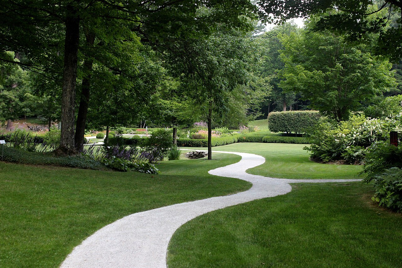 A curving gravel path across the lawns below the house