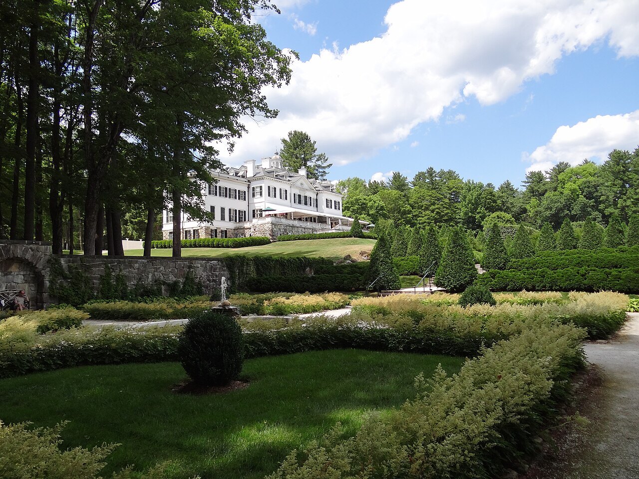 Clipped hedges and lawns in the formal garden, the house through the trees