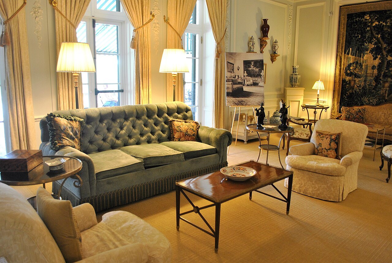 A drawing room at the Mount, sofas and lamps beneath tall curtained windows