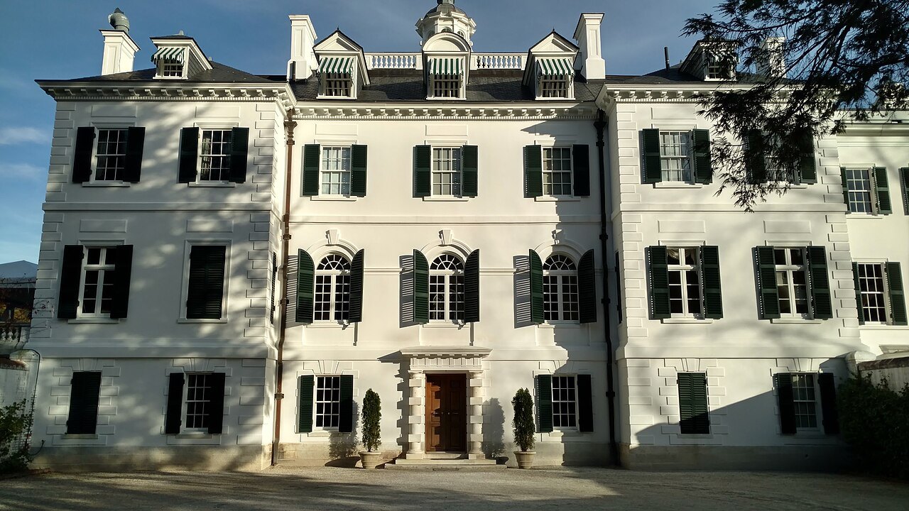 The white stucco front of the Mount with its dark green shutters in evening sun