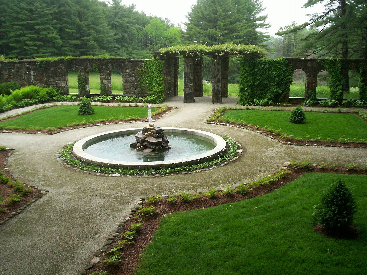 The fountain at the center of the walled garden, stone walls and arches behind