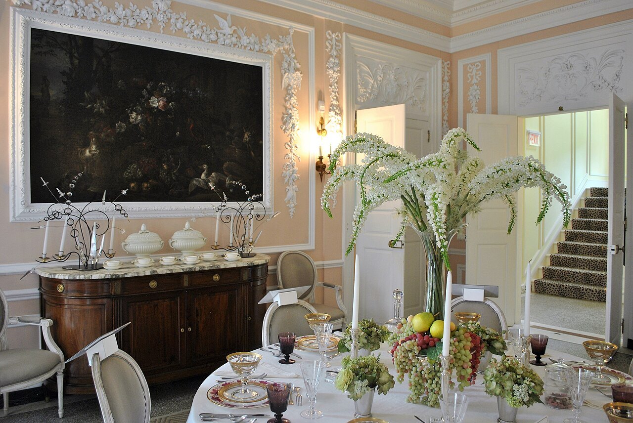 The dining room laid for a meal, a painting over the sideboard