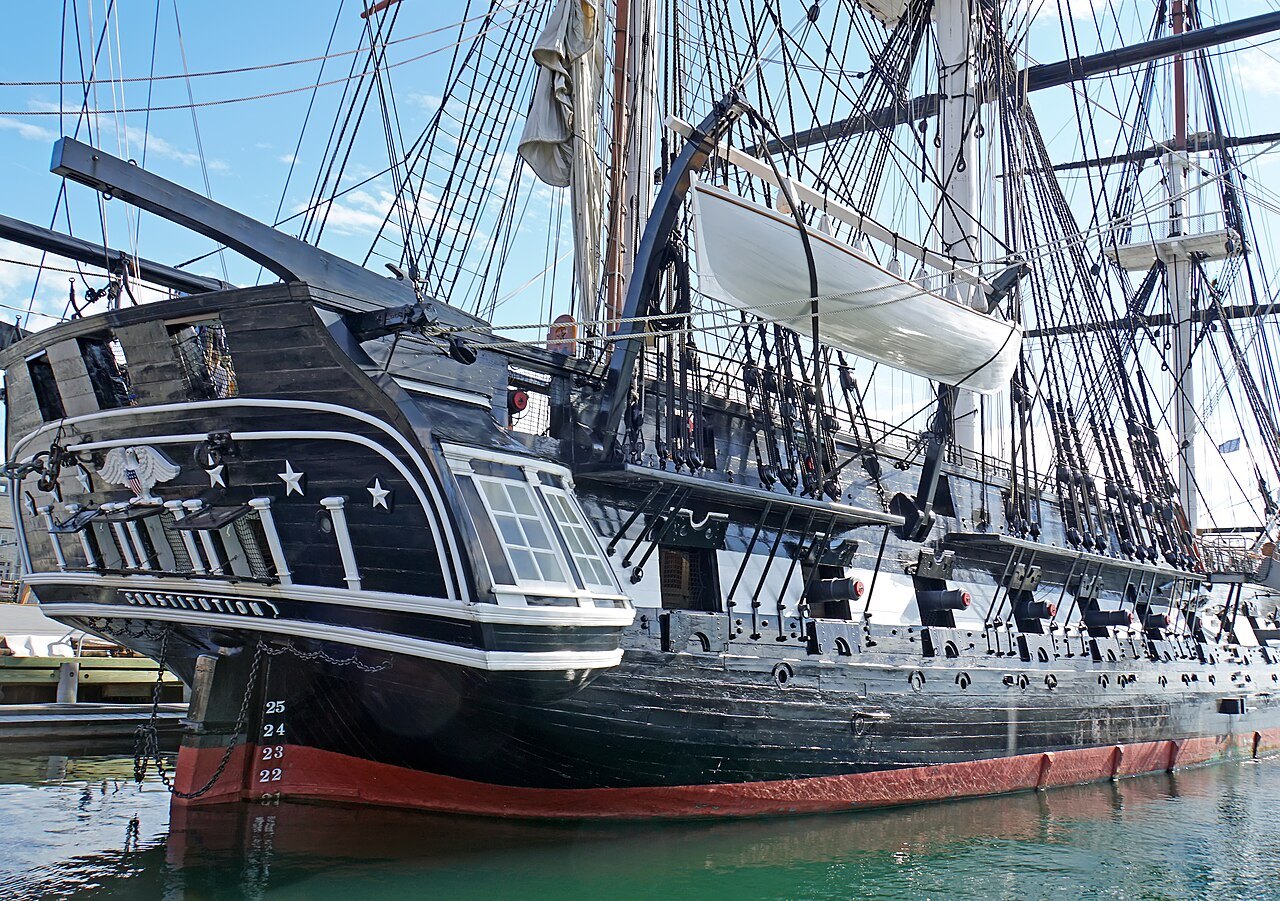The black hull and white gunport stripe of USS Constitution, her rigging overhead